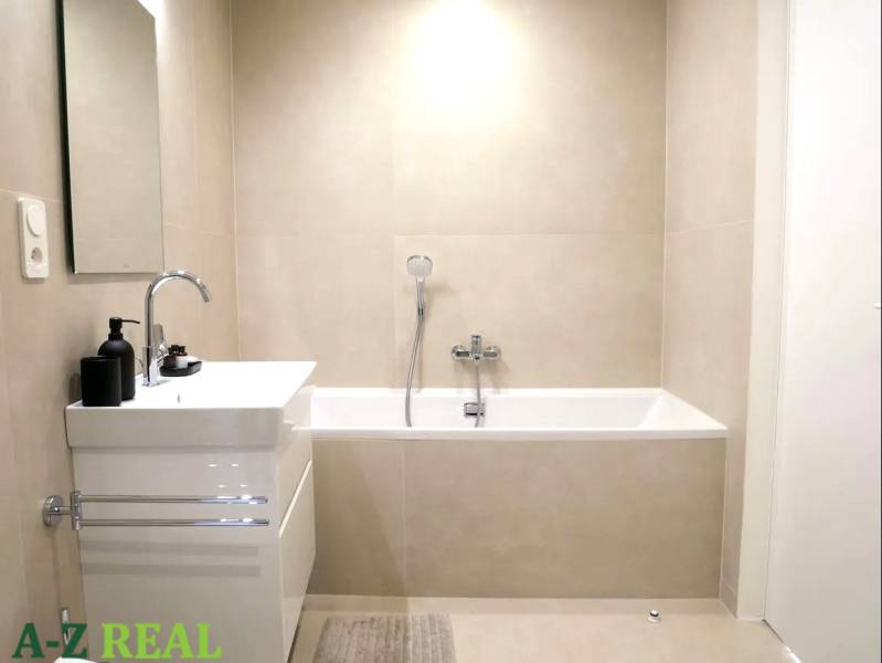 A bathroom with a bathtub and a sink in a 3-room apartment with simple furnishings.