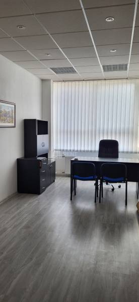 Offices with wood-patterned flooring, furnished with furniture and large windows.