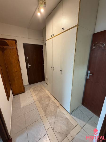 A hallway with built-in wardrobes and ceramic tiles in a 2-room apartment.