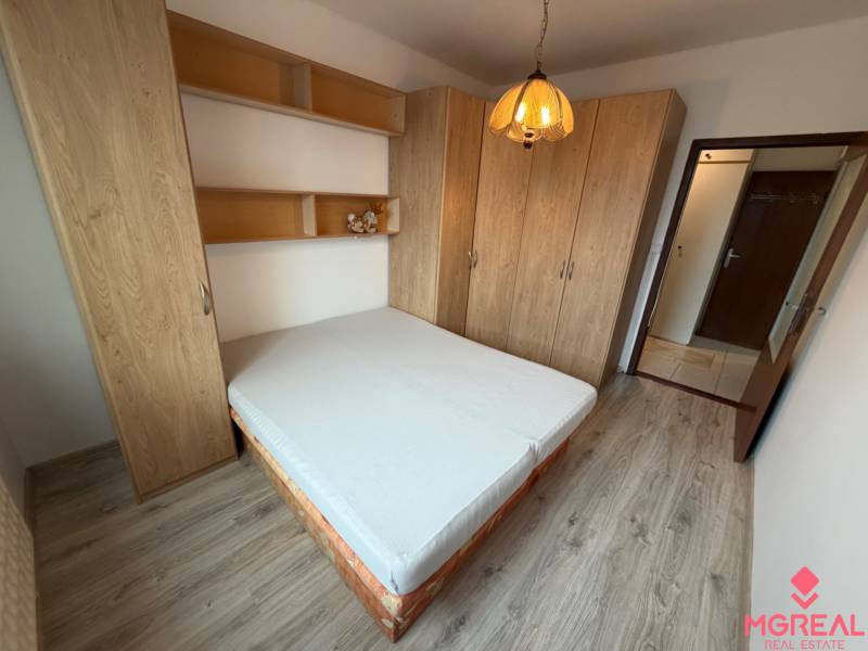 Bedroom in a two-room apartment with a double bed, built-in wardrobes, and a floor with a wooden decor.