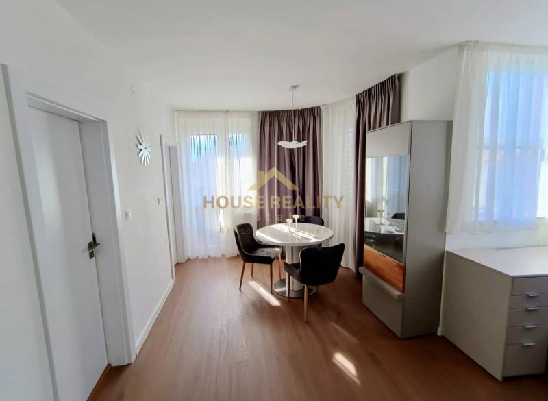 Dining area in a 2-room apartment with a round table and wooden decor flooring.
