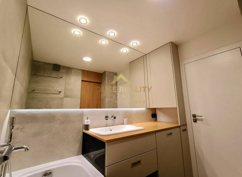 Bathroom in a 2-room apartment with a large mirror, sink, and bathtub.
