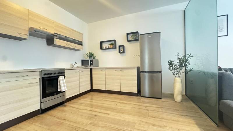 A kitchen in a 3-room apartment with a wooden decor floor and wall shelves.