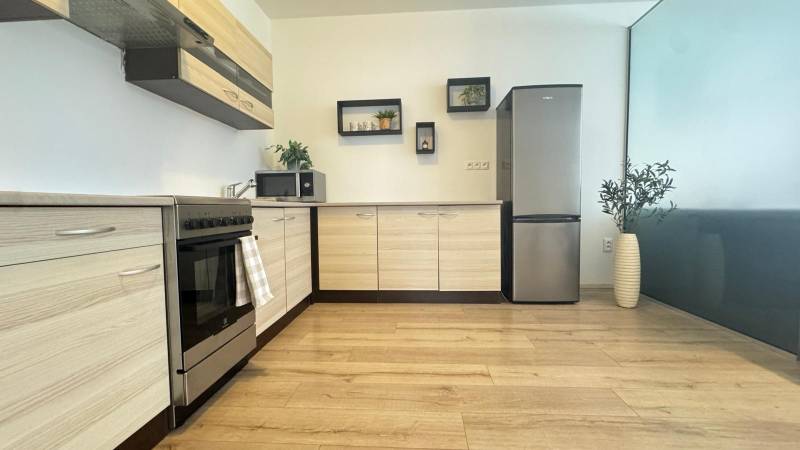 Kitchen in a 3-room apartment with a countertop and refrigerator, floor with wooden decor.