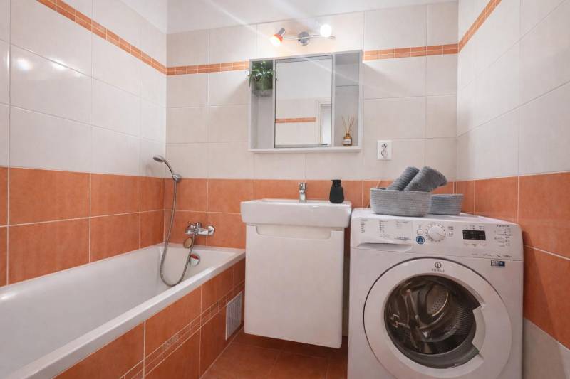 Bathroom with a bathtub, sink, and washing machine in a 3-room apartment.