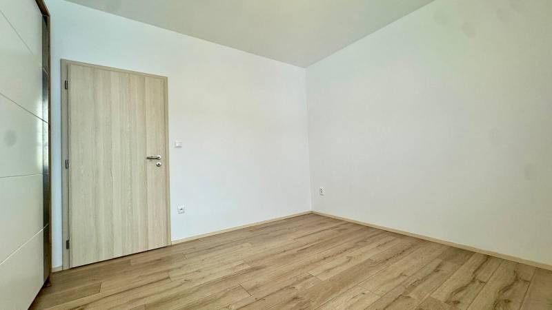 A room in a 3-room apartment with a wooden decor floor and white walls.