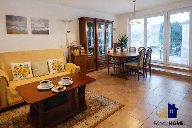 Living room in a family house with a dining table, shelves, and a sofa.