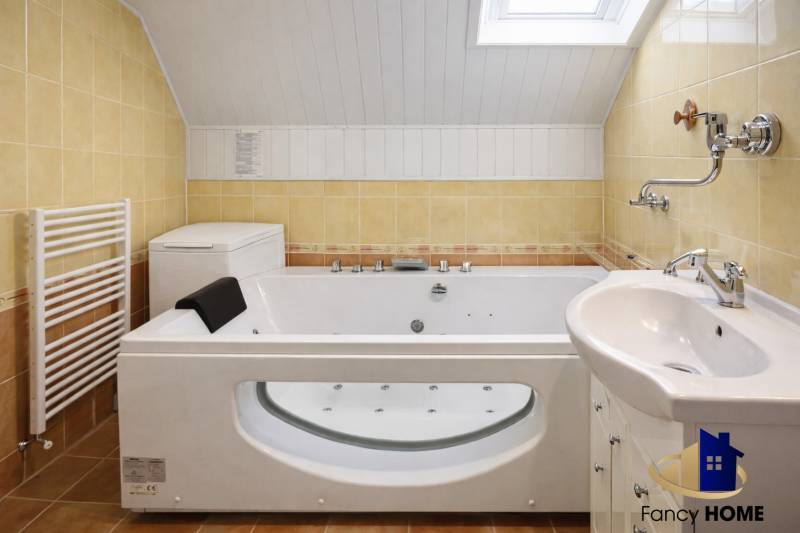 Bathroom with a hot tub and a washing machine in a family house, under a skylight.