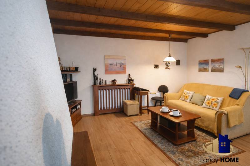 A living room in a family house with a wood-patterned floor, a comfortable couch, and decorations.