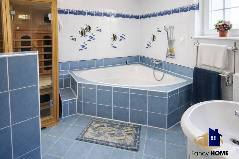 A large bathroom with a corner bathtub, blue tiles, and a sauna in a family house.