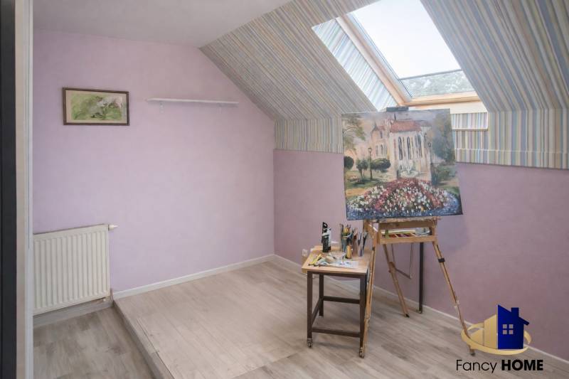 Attic studio with paintings in a family house, floor with wooden decor.