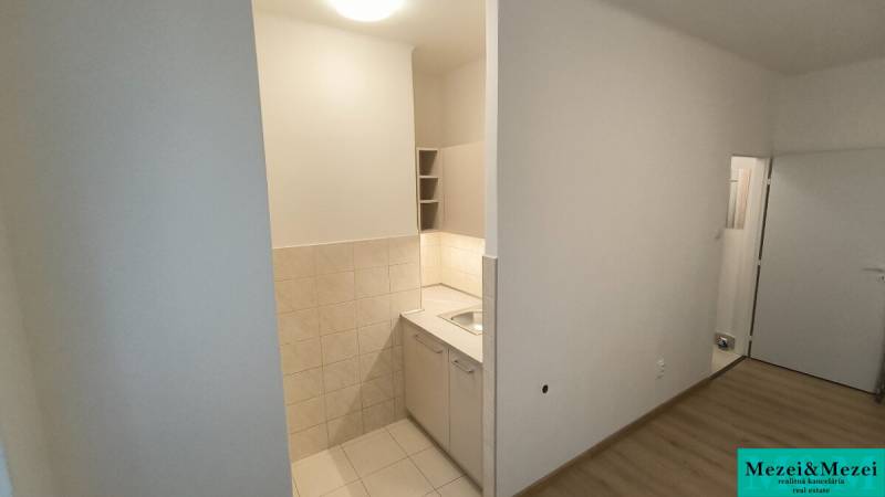 Kitchen corner in a studio apartment with a wooden decor floor and light tiles.