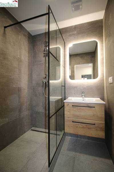 Elegant bathroom with a frameless shower enclosure and modern sink in a 3-room apartment.