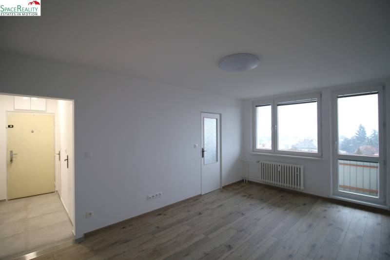 Living room in a 3-room apartment with windows, doors, and a floor with a wooden decor.