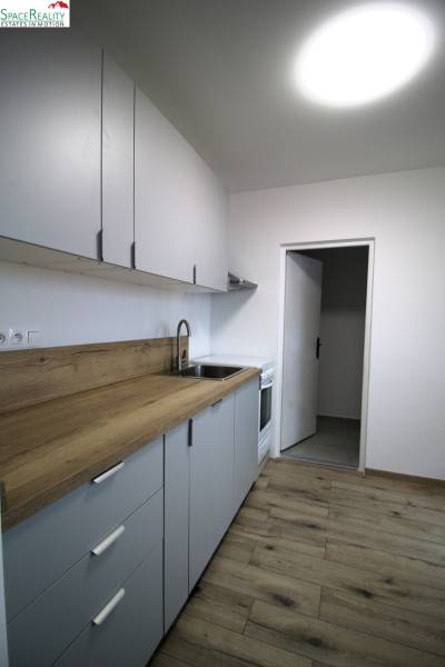 A kitchen in a 3-room apartment with a wooden decor floor and a functional wooden counter.