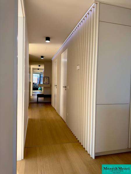 A narrow hallway in a 3-room apartment with a wood-patterned floor and white doors.
