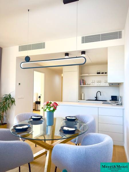 Dining room in a 3-room apartment with a wood-patterned floor and a glass table.