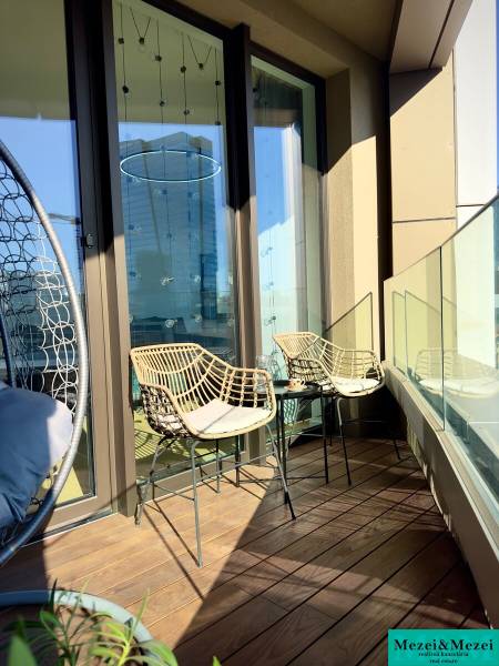 Balcony in a 3-room apartment with wicker chairs and a floor with a wooden decor.