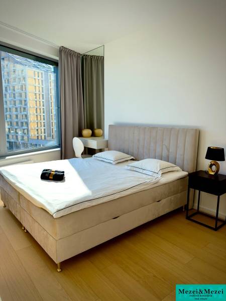 Bedroom with a bed and a table in a 3-room apartment with a wooden decor floor.