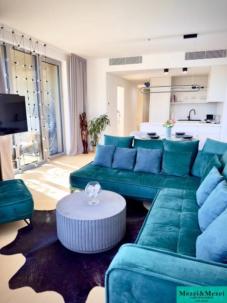 Living room with a turquoise sofa, round table, and wooden decor flooring.