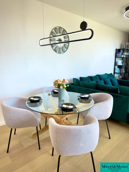 Dining table in a 3-room apartment with a round glass top and four chairs.