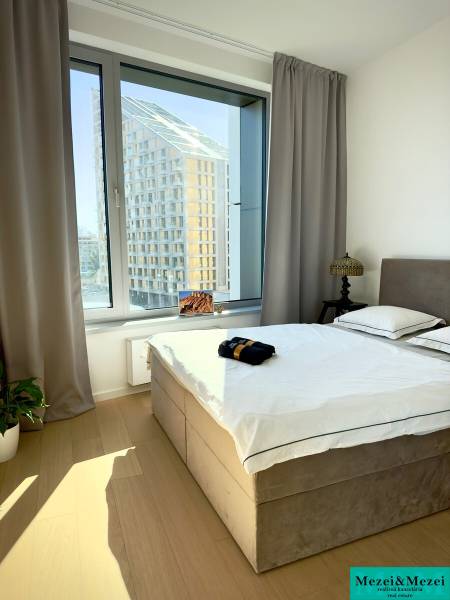 A bedroom with a large window, curtains, and a wooden decor floor in a 3-room apartment.