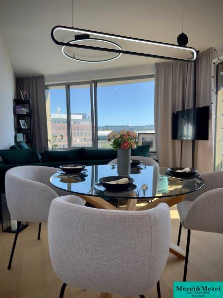 Dining area in a 3-room apartment with a round table and large windows.