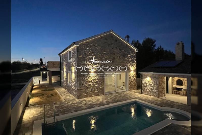 Night exterior of a family house in Vrsi with a stone facade and a pool on Vrsi street.
