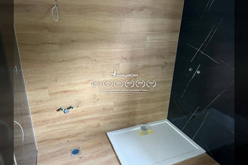 A bathroom in a family house with a wooden decor floor and dark tiles.