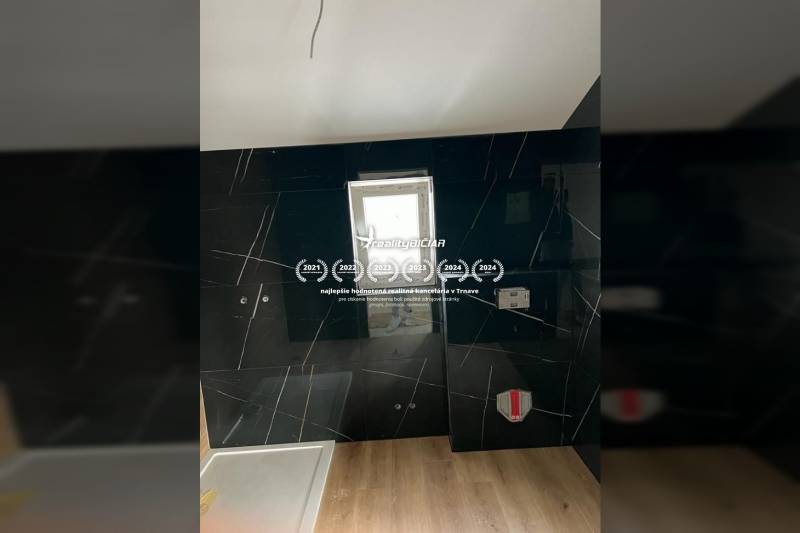 A bathroom with dark tiles and a wooden decor floor in a family house.