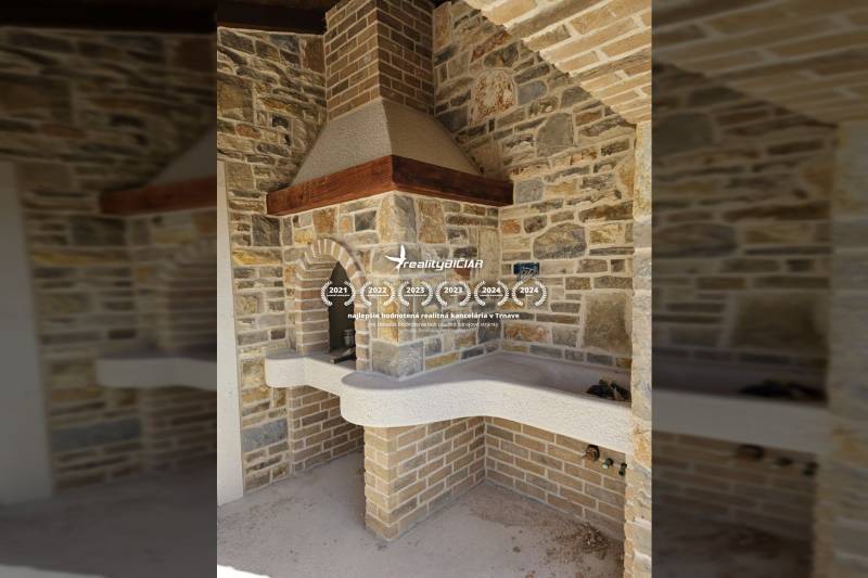 A fireplace with stone cladding in a family house, decorated with brick details.