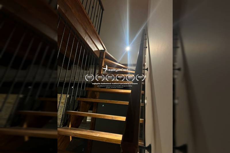 A staircase with a railing leads to the upper floor in a family house, with a wooden decor floor.