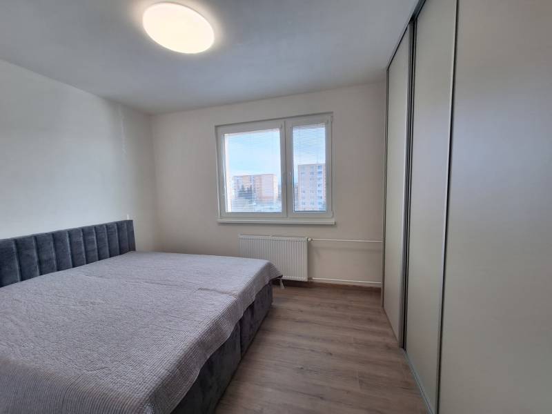 A bedroom with a bed, a wardrobe, and a wooden decor floor in a two-room apartment.