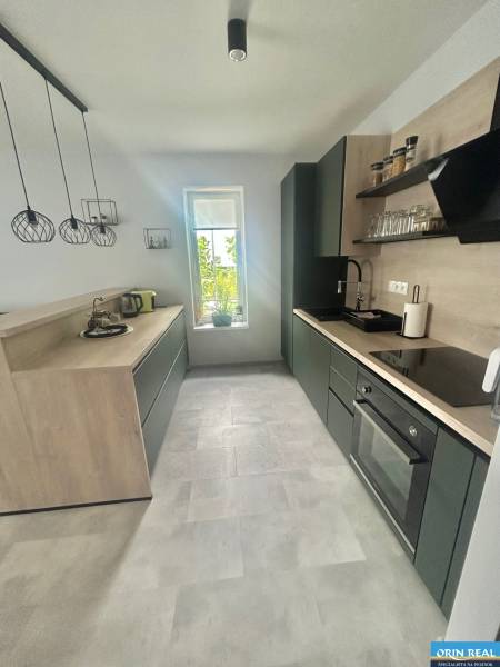 A kitchen in a two-room apartment with black cabinets and a gray floor.