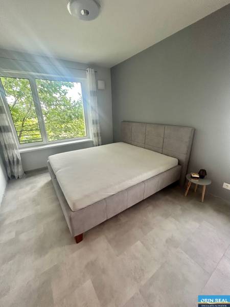 A bedroom in a two-room apartment with a large window and a comfortable bed.