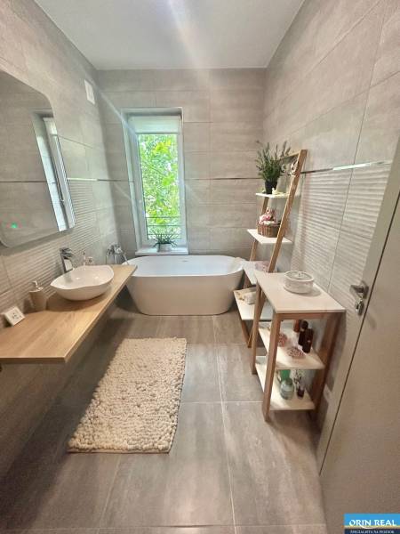 A stylish bathroom in a 2-room apartment with a bathtub, a sink on a wooden countertop, and decorations.