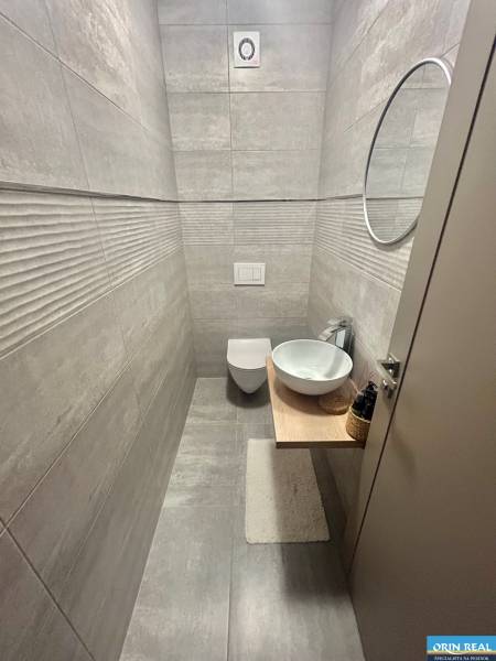 Bathroom in a 2-room apartment with a sink on wooden decor and modern tiles.