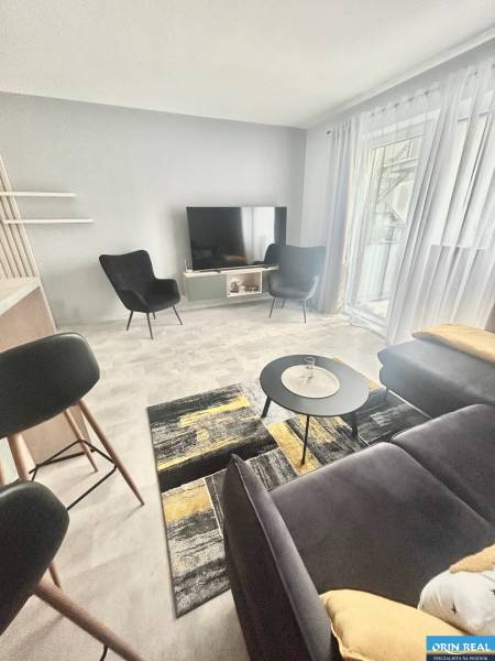 Living room in a two-room apartment with a grey sofa and black armchairs.