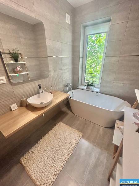 A bathroom in a 2-room apartment with a freestanding bathtub and a large window.