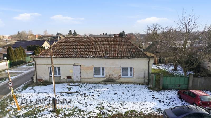 A family house in Zemné with a shabby facade, snow cover on the property - living.