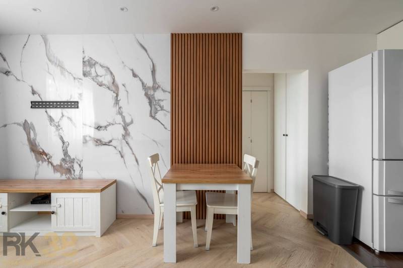Dining area with a table and chairs, marble wall, wooden decor flooring in a 3-room apartment.