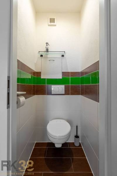 A bathroom in a 3-room apartment with striking green-brown tiles and sanitary ware.
