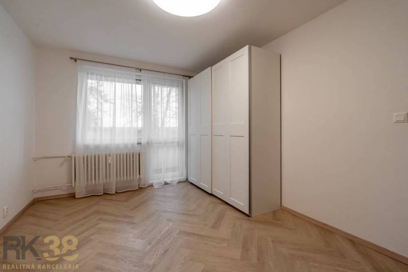 Interior of a spacious 3-room apartment with a wardrobe and wooden decor flooring.