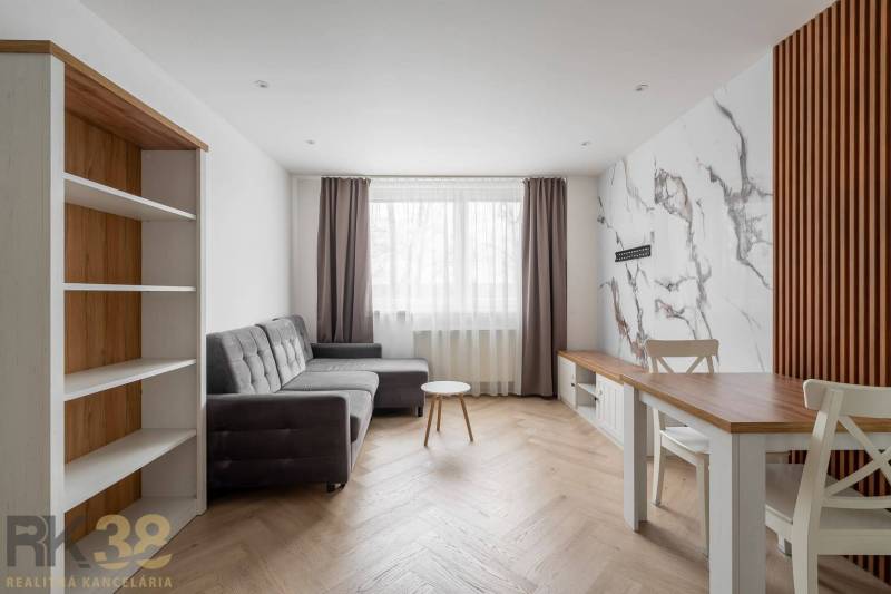 Living room in a 3-room apartment with a wooden decor floor and a gray sofa.
