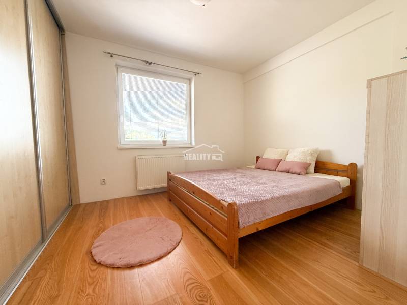 Bedroom in a 2-room apartment with a bed, wardrobe, and wooden decor flooring.