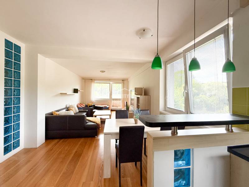 Living area of a 2-room apartment with a wooden decor floor and green lighting fixtures.