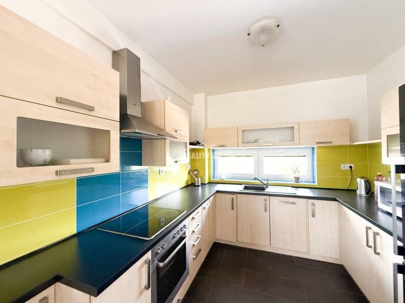 The kitchen of a 2-room apartment with colorful tiles and light cabinets.