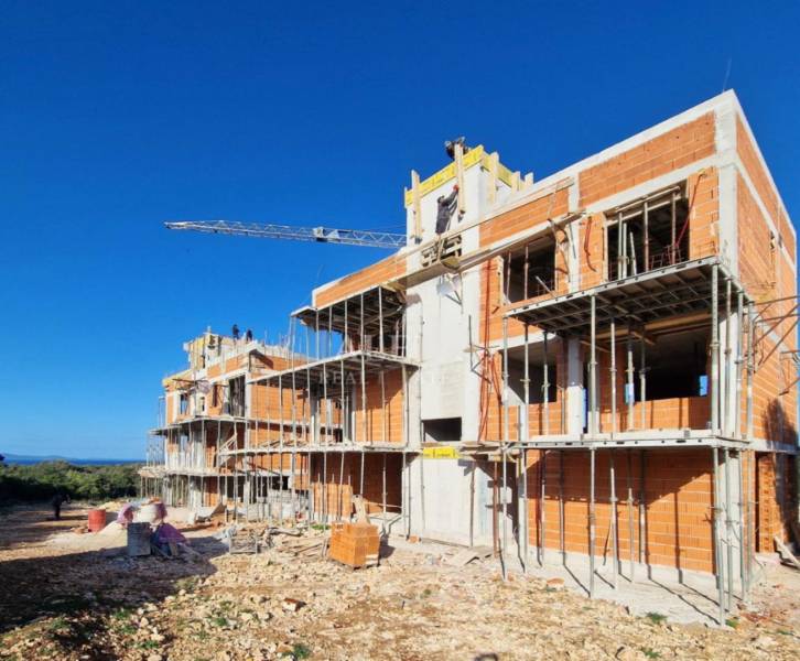 Construction of apartments in Petrčane, a building under construction with scaffolding and a crane is visible.