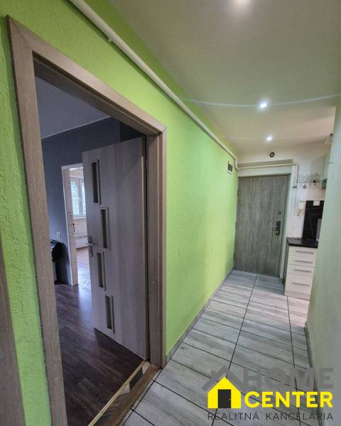 A hallway in a 3-room apartment with an entrance to a floor with a wooden decor and a green wall.