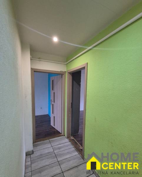 Hallway of a 3-room apartment with ceramic tiles and colorful walls, open doors to the rooms.